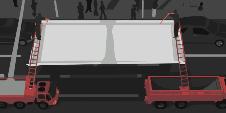 Over-the-street banner suspended across a city street with buildings in the background